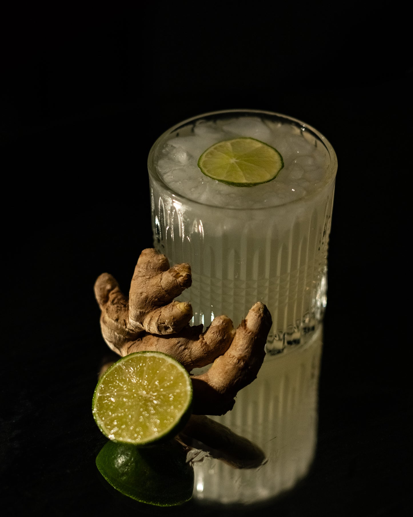 Glass of ginger ale with a lime wedge on a dark background