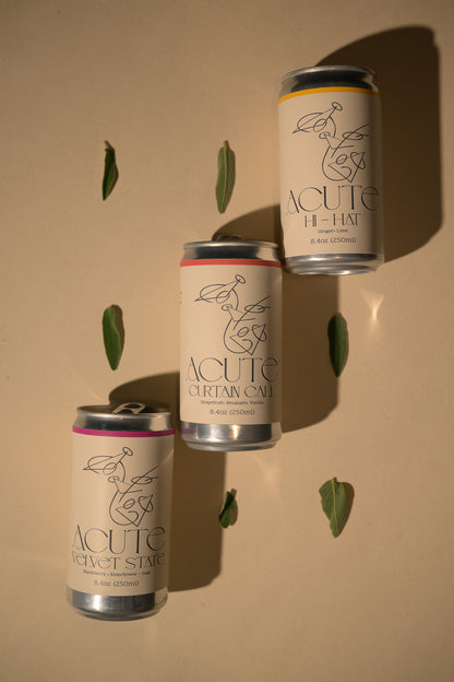 Three cans of Acute High Hat on a beige background with sage leaves.