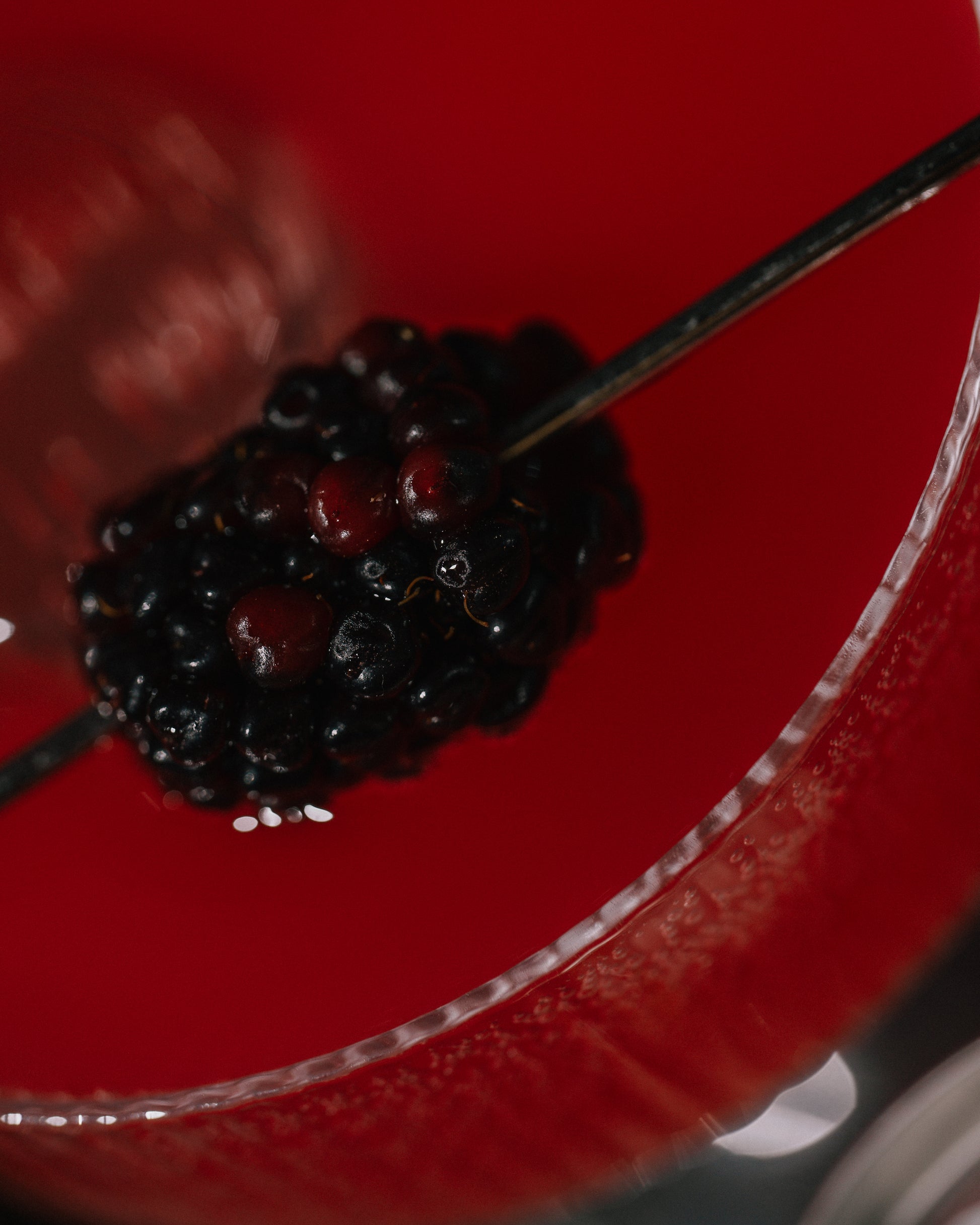 Close-up of a skewer with black berries on a red coupe