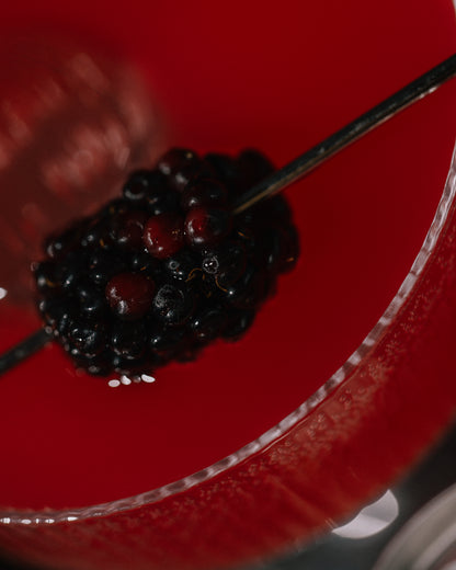 Close-up of a skewer with black berries on a red coupe